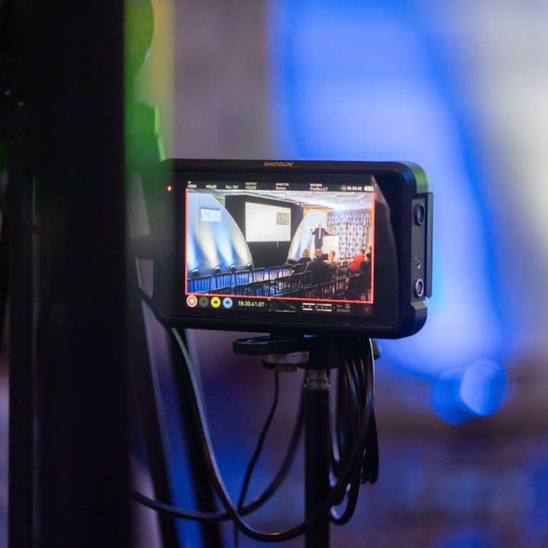Image of a camera taking a shot of stage set ready to record an event session.